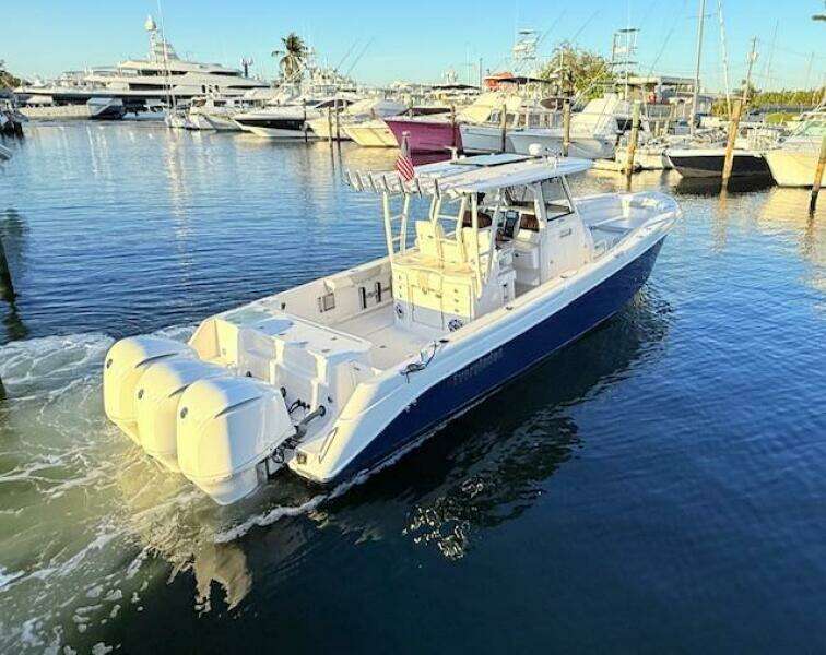 2014 Everglades 355 Center Console boat docked in marina, featuring triple outboard engines.