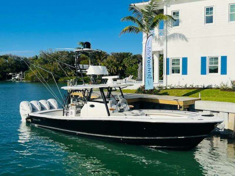 2024 Regulator 41 boat docked by a waterfront house with palm trees.