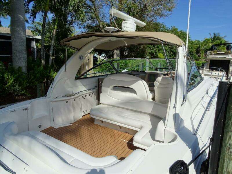 2001 Sea Ray 410 Sundancer yacht with spacious deck and seating, docked near lush greenery.