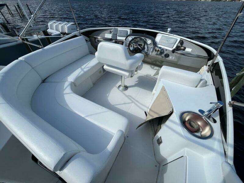 2000 Carver 396 Motor Yacht cockpit with white seating and steering, overlooking water.