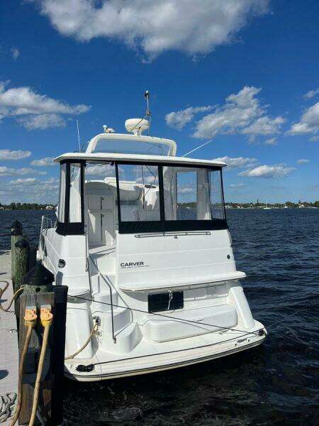 2000 Carver 396 Motor Yacht docked by a scenic waterfront under a clear blue sky.
