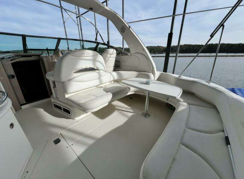 2001 Sea Ray 380 Sundancer yacht interior with white seating and table, overlooking water.