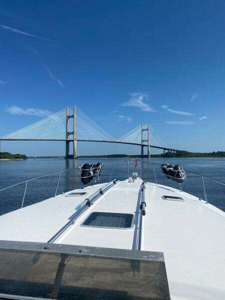 1993 Sea Ray 440 Sundancer cruising towards a suspension bridge under clear blue skies.