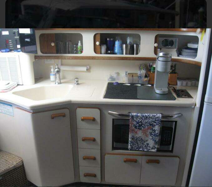 Interior of 1993 Sea Ray 440 Sundancer yacht kitchen with sink, stove, and storage.