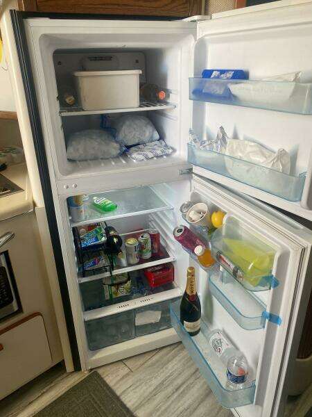 Open refrigerator in a 1993 Sea Ray 440 Sundancer, stocked with drinks and food items.