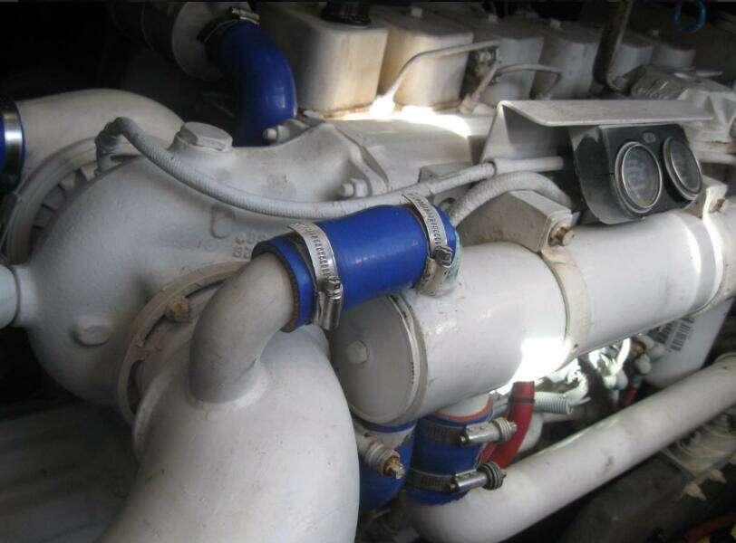 Engine components of a 1993 Sea Ray 440 Sundancer with blue hoses and clamps.