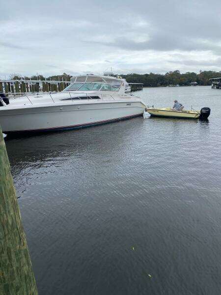 1993 Sea Ray 440 Sundancer docked beside a small yellow boat on a cloudy day.