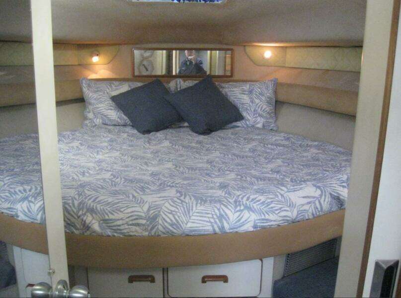 1993 Sea Ray 440 Sundancer cabin with a cozy bed and decorative pillows.