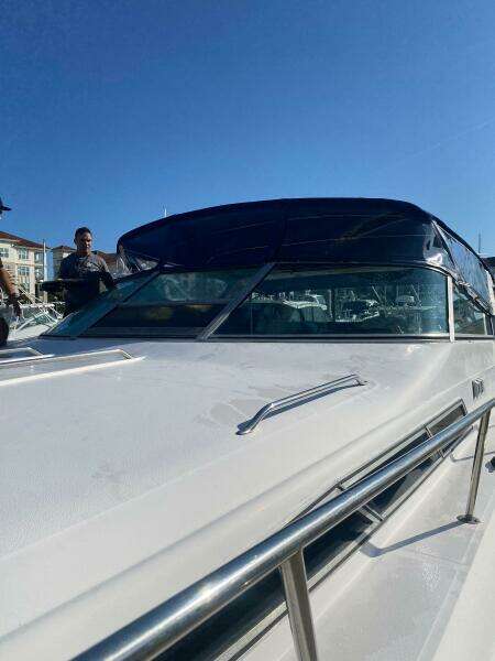 1993 Sea Ray 440 Sundancer yacht with sleek design and blue canopy under clear sky.