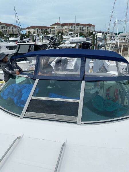 1993 Sea Ray 440 Sundancer docked at marina with blue canopy and nearby buildings.