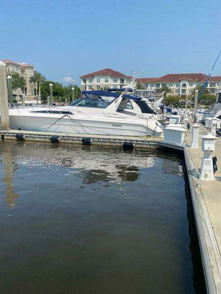 1993 Sea Ray 440 Sundancer docked at a marina with waterfront buildings in the background.