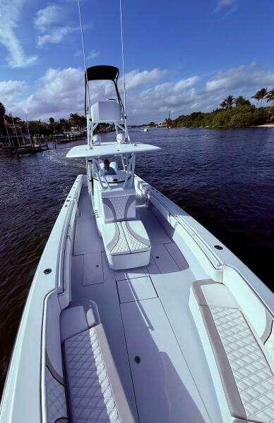 2024 Contender 39 ST boat cruising on a scenic waterway under a clear blue sky.