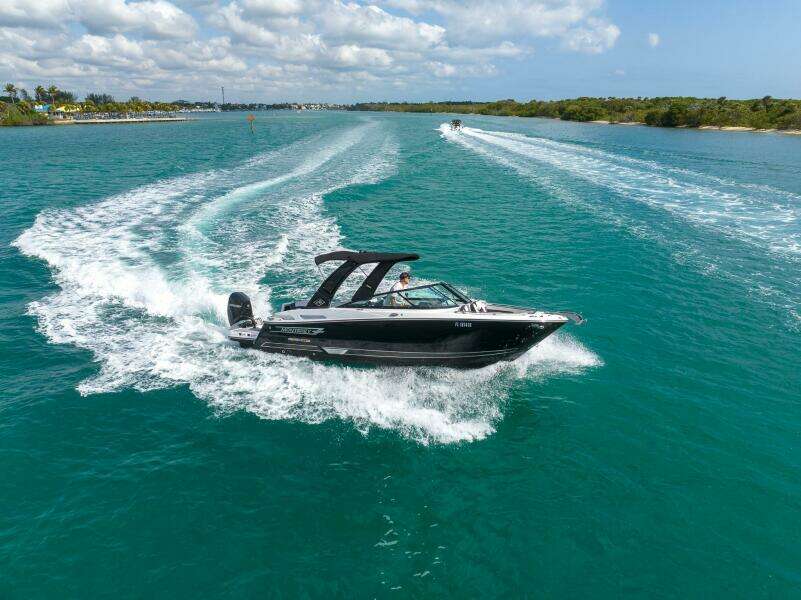 2023 Monterey 255 Super Sport boat cruising on clear blue water under a partly cloudy sky.