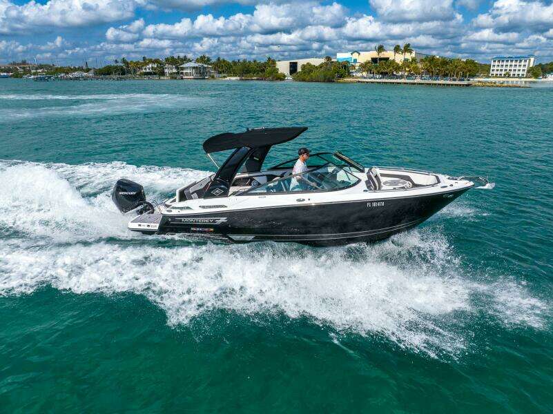 2023 Monterey 255 Super Sport boat cruising on turquoise water under a partly cloudy sky.