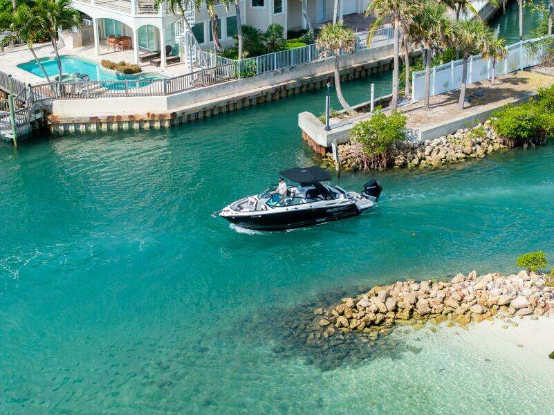 2023 Monterey 255 Super Sport boat cruising in a scenic coastal waterway near luxury homes.