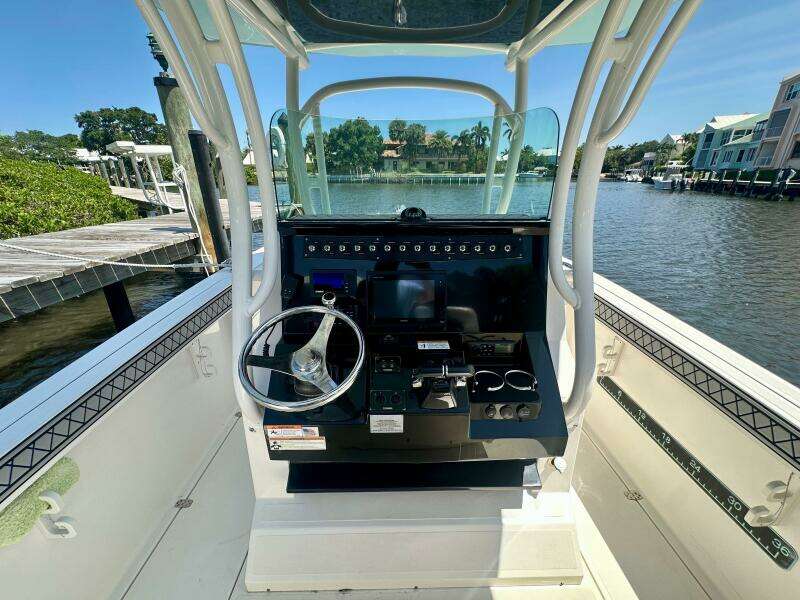 2019 Wellcraft 262 Fisherman boat console with steering wheel, docked by a scenic waterfront.