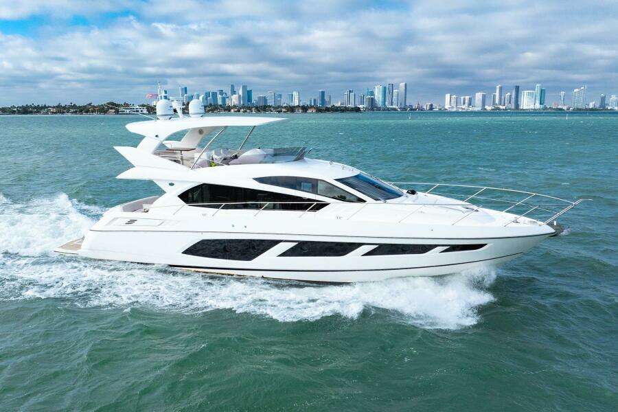 2016 Sunseeker Manhattan 65 yacht cruising on open water with city skyline backdrop.