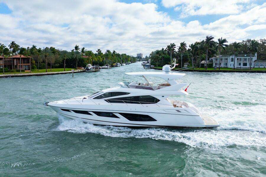 2016 Sunseeker Manhattan 65 yacht cruising on a scenic waterway with palm trees.