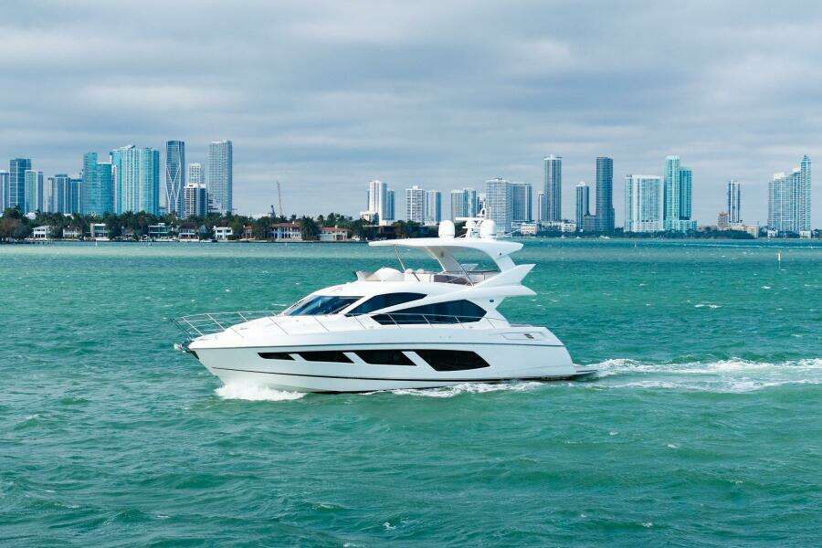 2016 Sunseeker Manhattan 65 yacht cruising near a city skyline.