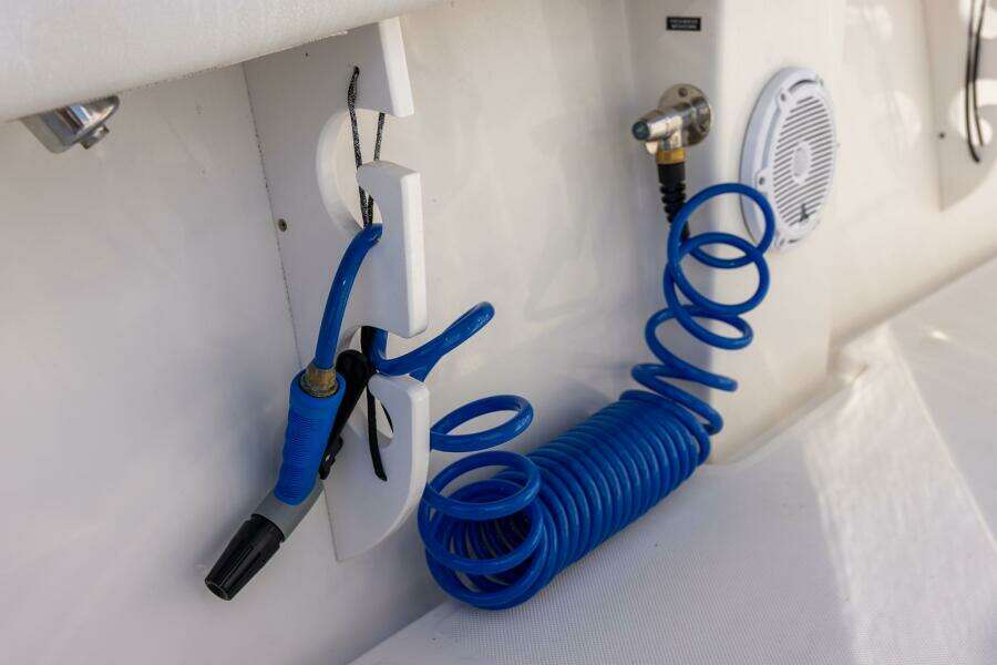 Blue coiled hose and nozzle on 2018 Jupiter 26 FS boat deck.