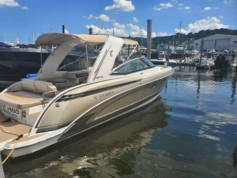 2015 Formula 330 Crossover Bowrider docked at marina under blue sky.