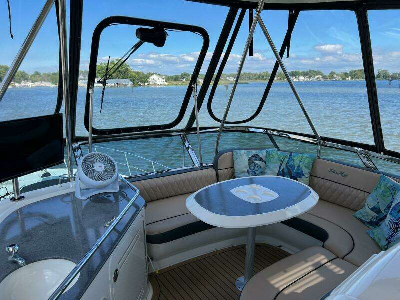 2005 Sea Ray 500 Sedan Bridge interior with seating and table, overlooking serene water view.