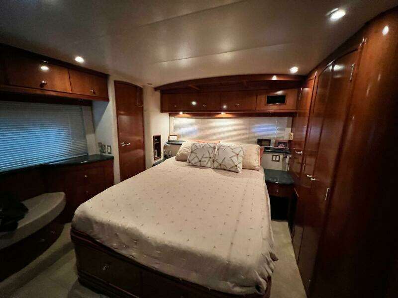 Luxurious bedroom interior of 2000 Carver 506 Motor Yacht with wood cabinetry and cozy lighting.