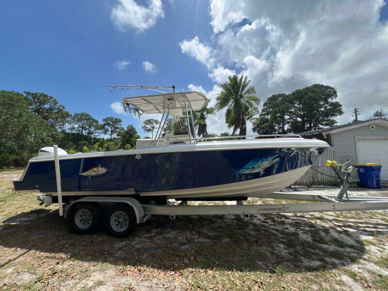 1998 Blue Fin 25 Center Console boat on trailer, parked outdoors under cloudy sky.