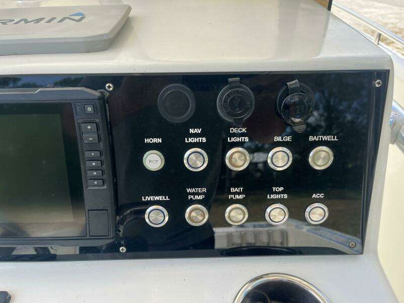 Control panel of a 1998 Blue Fin 25 Center Console boat with various switches and a Garmin device.