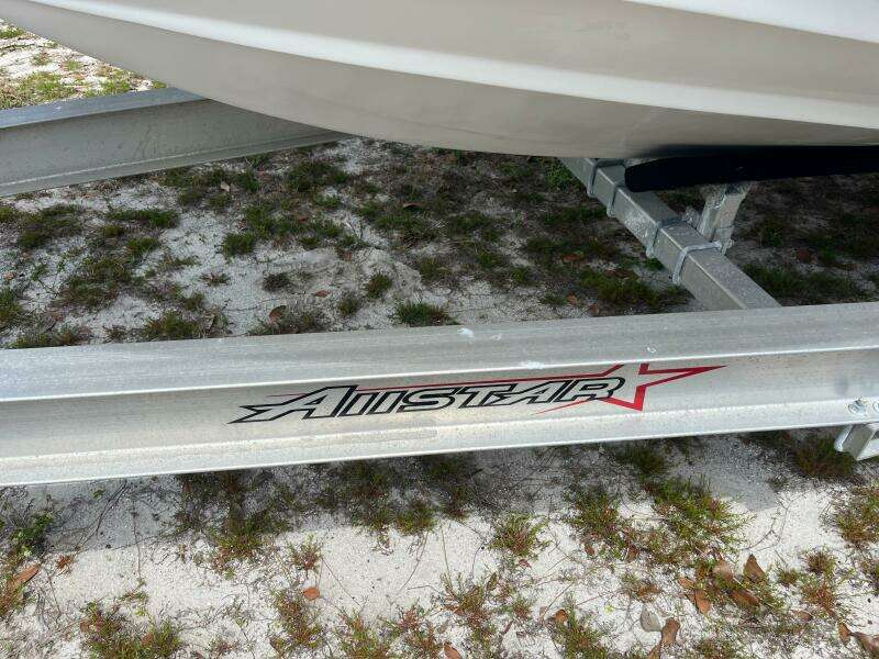 Trailer for 1998 Blue Fin 25 Center Console boat on sandy ground.