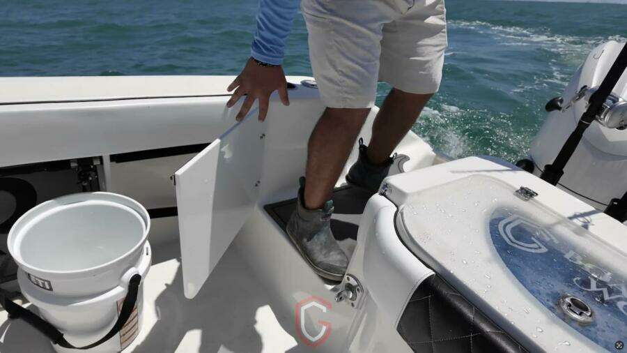 Person on 2023 CG Boat Works 35 M-Series, accessing storage compartment on deck.