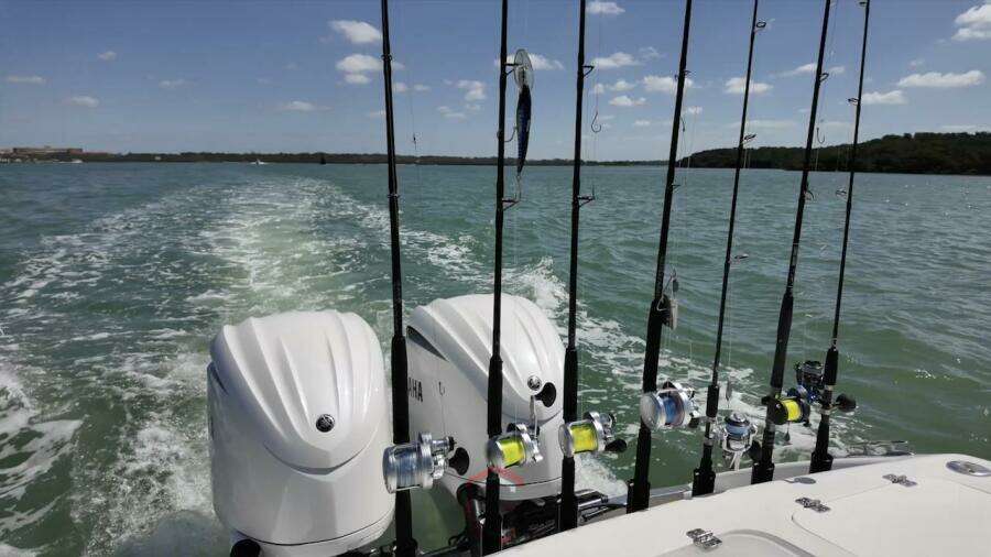 2023 CG Boat Works 35 M-Series with fishing rods and dual outboard motors on open water.
