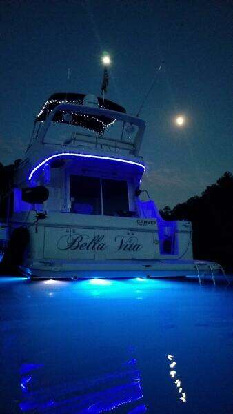 2004 Carver 360 Sport Sedan yacht illuminated at night with blue lights under a moonlit sky.