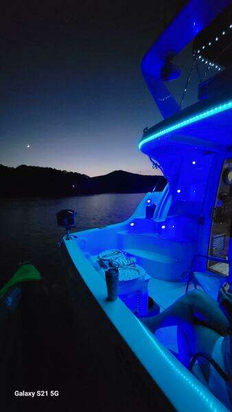 2004 Carver 360 Sport Sedan with blue LED lights on a serene lake at dusk.