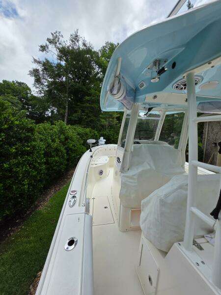 2021 Cobia 301 Center Console boat with covered seating, docked near lush greenery.