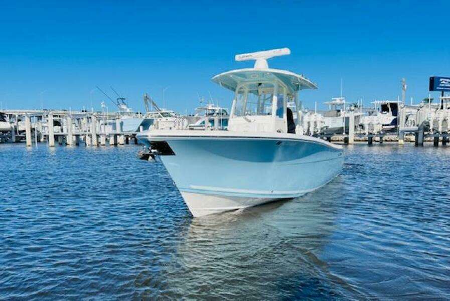 2021 Cobia 301 Center Console boat docked in marina under clear blue sky.