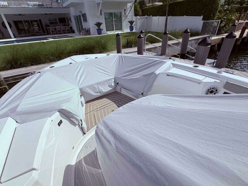 2024 Scout 400 LXF boat covered at dockside near modern waterfront home.