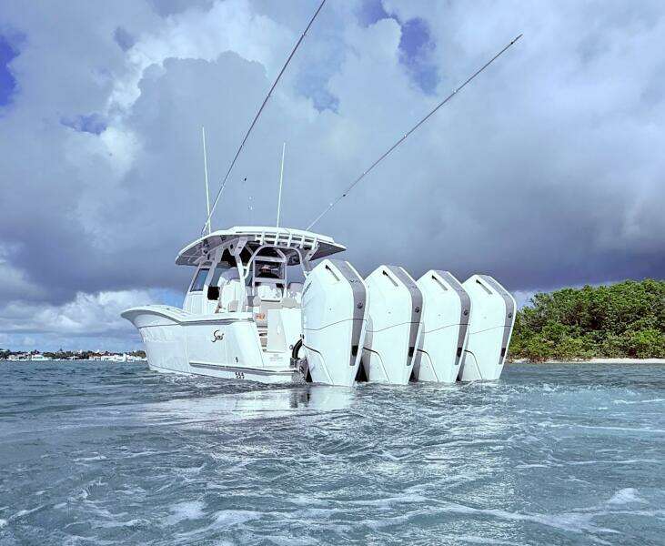2024 Scout 400 LXF boat with multiple engines cruising on water under cloudy skies.
