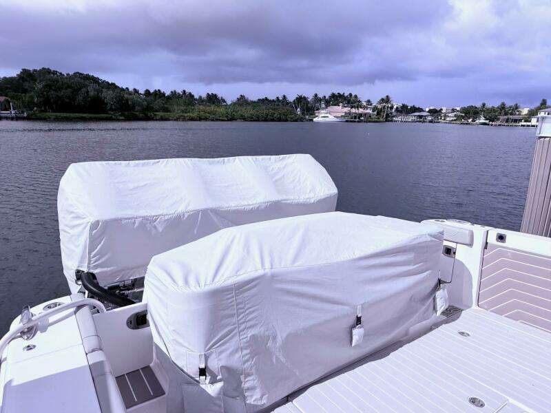 2024 Scout 400 LXF boat with covered engines docked by a scenic waterfront.