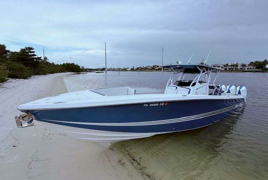 2022 Nor-Tech 390 Sport Center Console boat on sandy beach, calm waters, overcast sky.