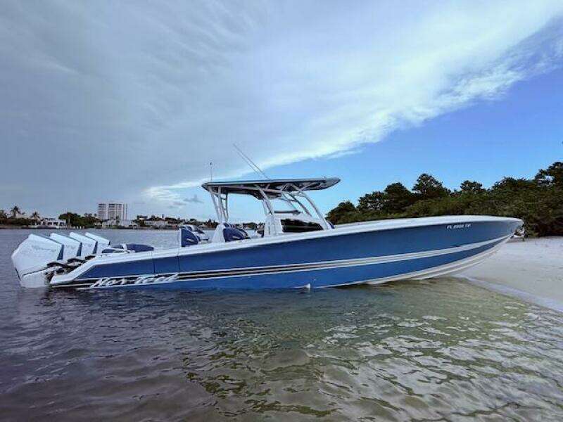2022 Nor-Tech 390 Sport Center Console boat on a sandy beach with cloudy sky.