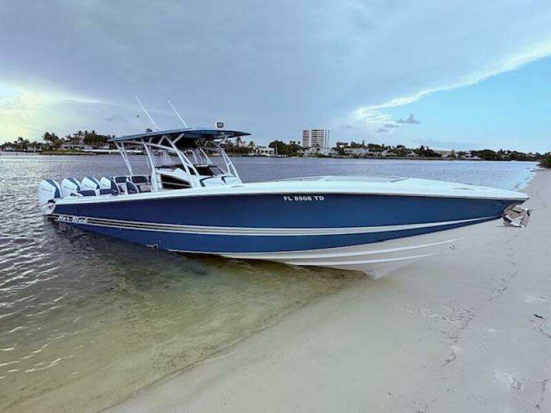 2022 Nor-Tech 390 Sport Center Console boat on sandy shore, calm waters, and cloudy sky.