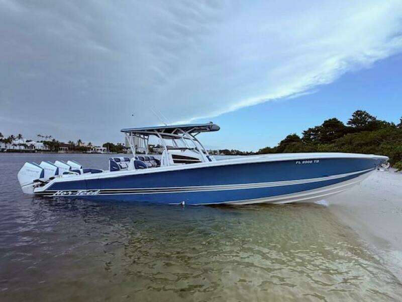 2022 Nor-Tech 390 Sport Center Console boat on sandy shore, under a cloudy sky.