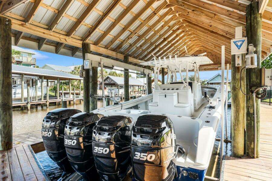 2015 Yellowfin 39 boat with triple 350 engines docked under a wooden shelter.