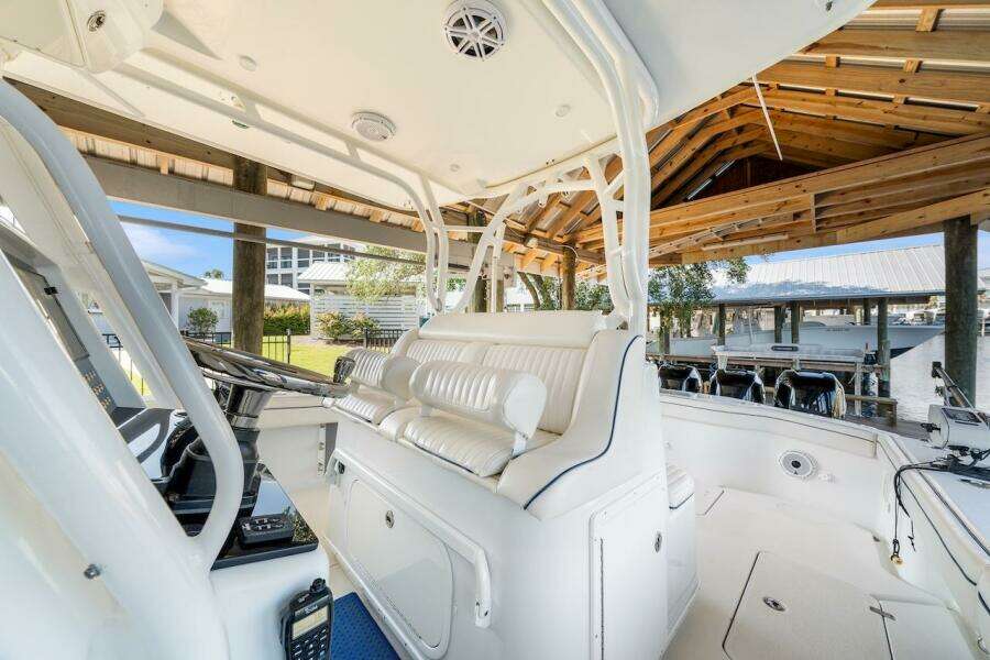 2015 Yellowfin 39 boat interior with white seating and helm under a wooden dock shelter.