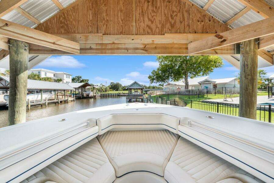 2015 Yellowfin 39 boat docked under wooden shelter, overlooking serene waterfront and residential area.
