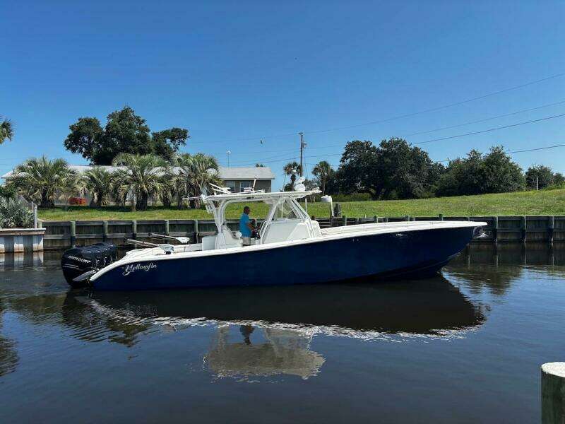 2015 Yellowfin 39 boat on calm water, clear sky, and lush greenery in the background.