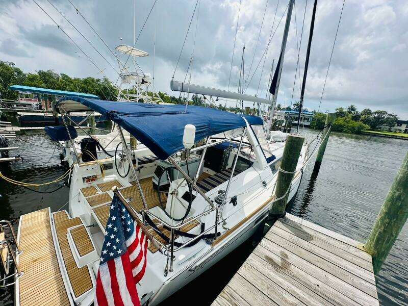 2015 Beneteau Oceanis 45 sailboat docked, featuring blue canopy and American flag.