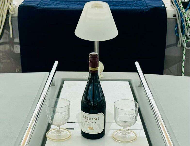 Bottle of Meiomi Pinot Noir with glasses on Beneteau Oceanis 45 yacht table.
