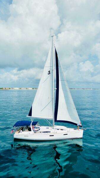2015 Beneteau Oceanis 45 sailing on calm blue waters under a cloudy sky.